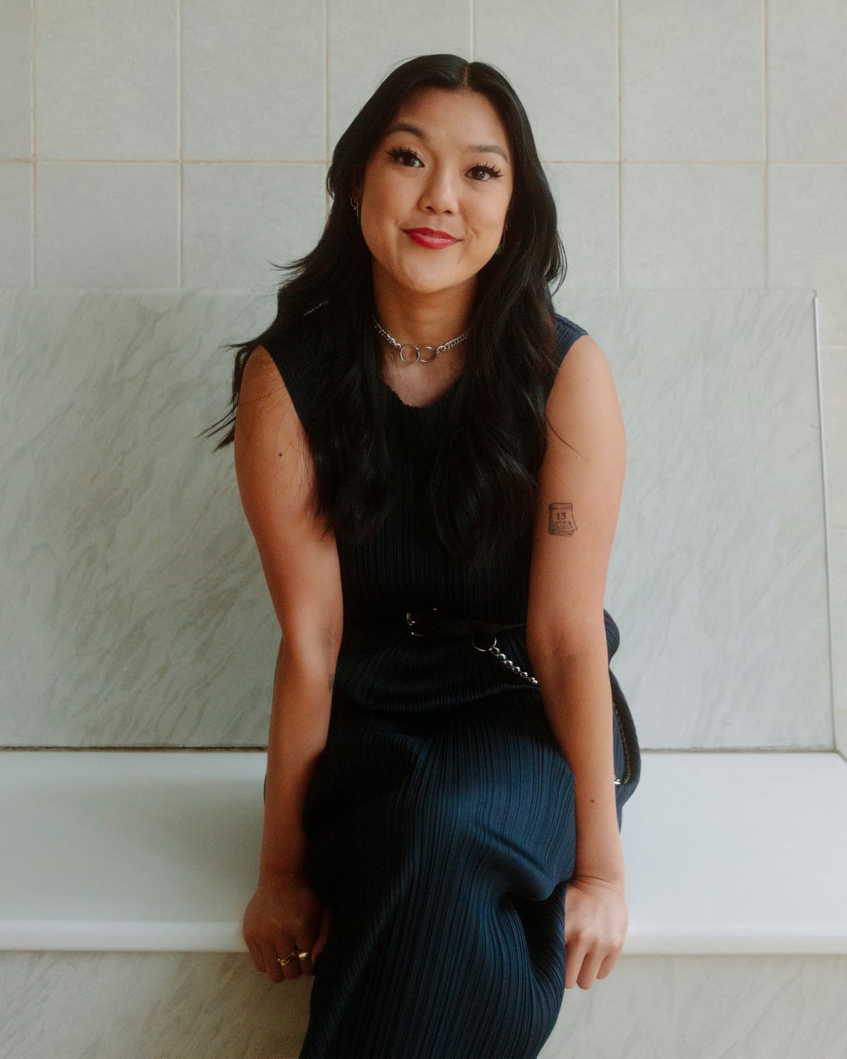 Angela Hui in a black dress, seated and looking at the camera. 