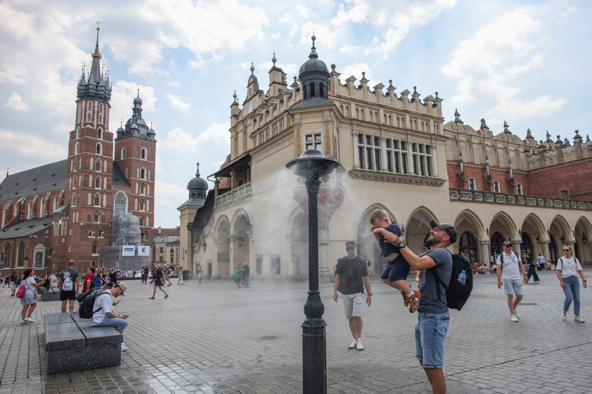 A man and child under a water sprinkler to cool off.