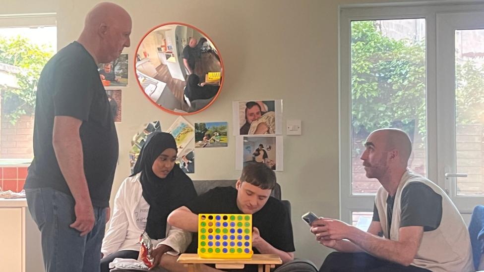 Two men and a woman sitting around a coffee table playing a game.