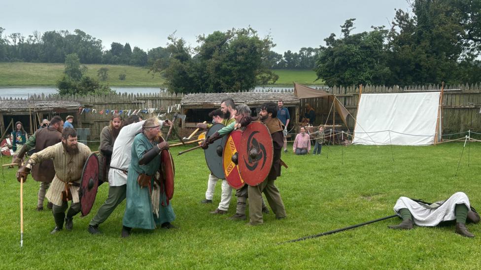 A group of men reenacting a Viking battle in a field. 