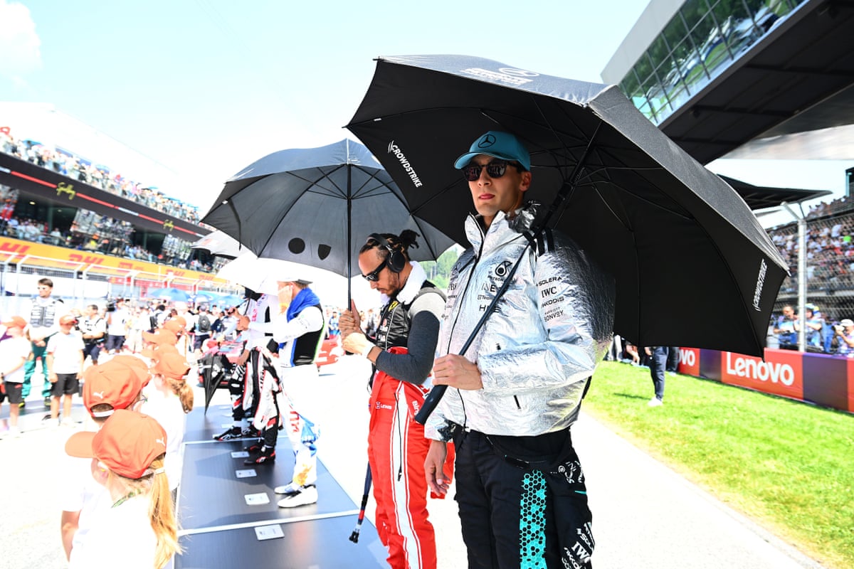 Lewis Hamilton and George Russell under umbrellas on the grid before the race
