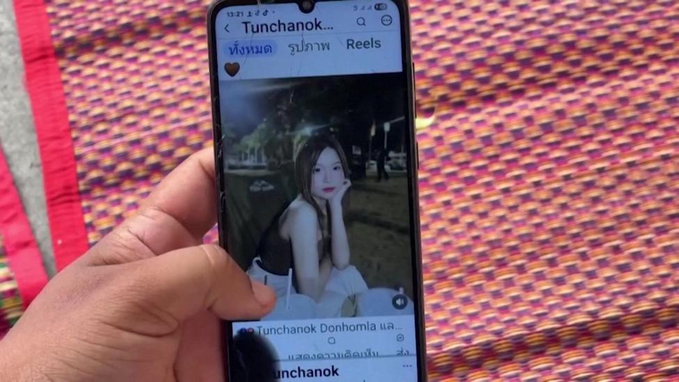 A close-up shot of a mobile phone on which an Instagram account belonging to the victim shows an image of her. She is a young woman with long brown hair and is posing with her chin rested on her hand in the evening.