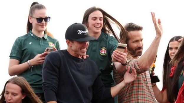 Rob Mac (left) and Ryan Reynolds with members of the Wrexham Women's team on a bus parade following their promotion to the Adran Premier in 2023.