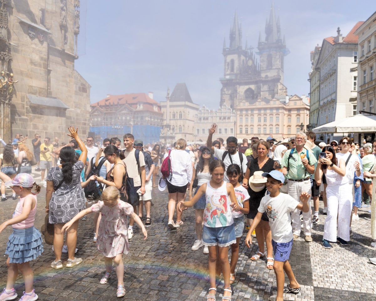 People are sprayed with water to cool down during a hot, sunny day, as the country records temperatures above 40 degrees Celsius in Prague, Czech Republic.