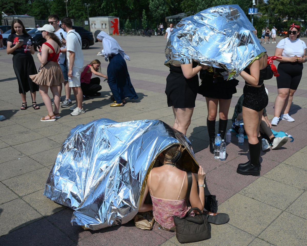 People use emergency blankets to protect them from the heat as the arrive at the Olympic stadium for a concert of US singer Bruno Mars in Berlin, Germany.