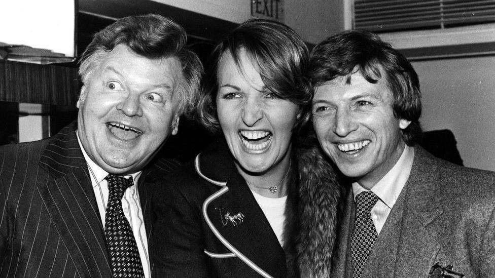 A black and white photo of Benny Hill, Penelope Keith, Tommy Steele