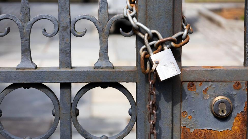 A locked iron gate with a padlock around it