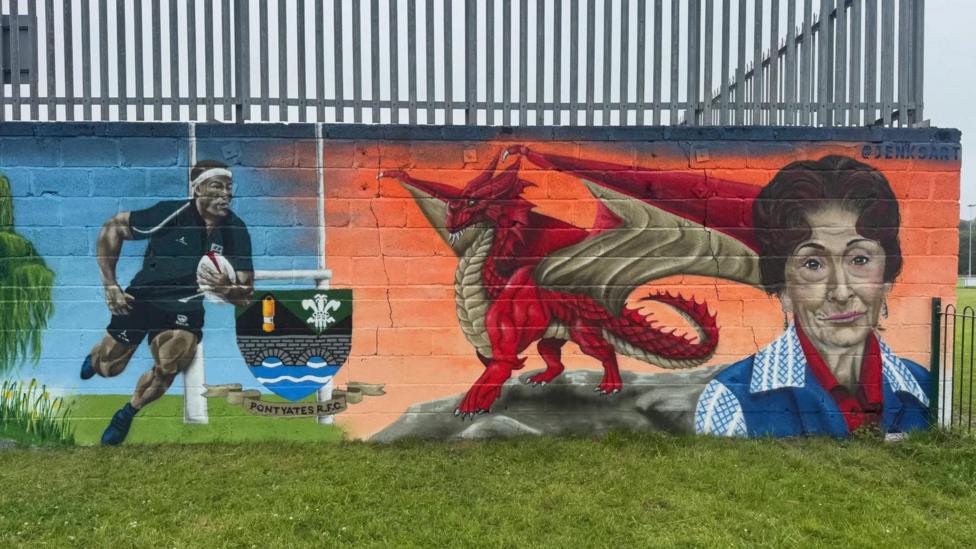 Mural in Pontyates featuring a rugby player, a red dragon and Dot Cotton