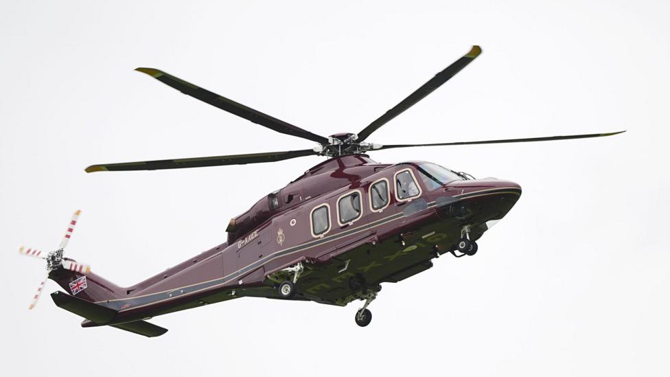 A dark purple-coloured helicopter in the sky.