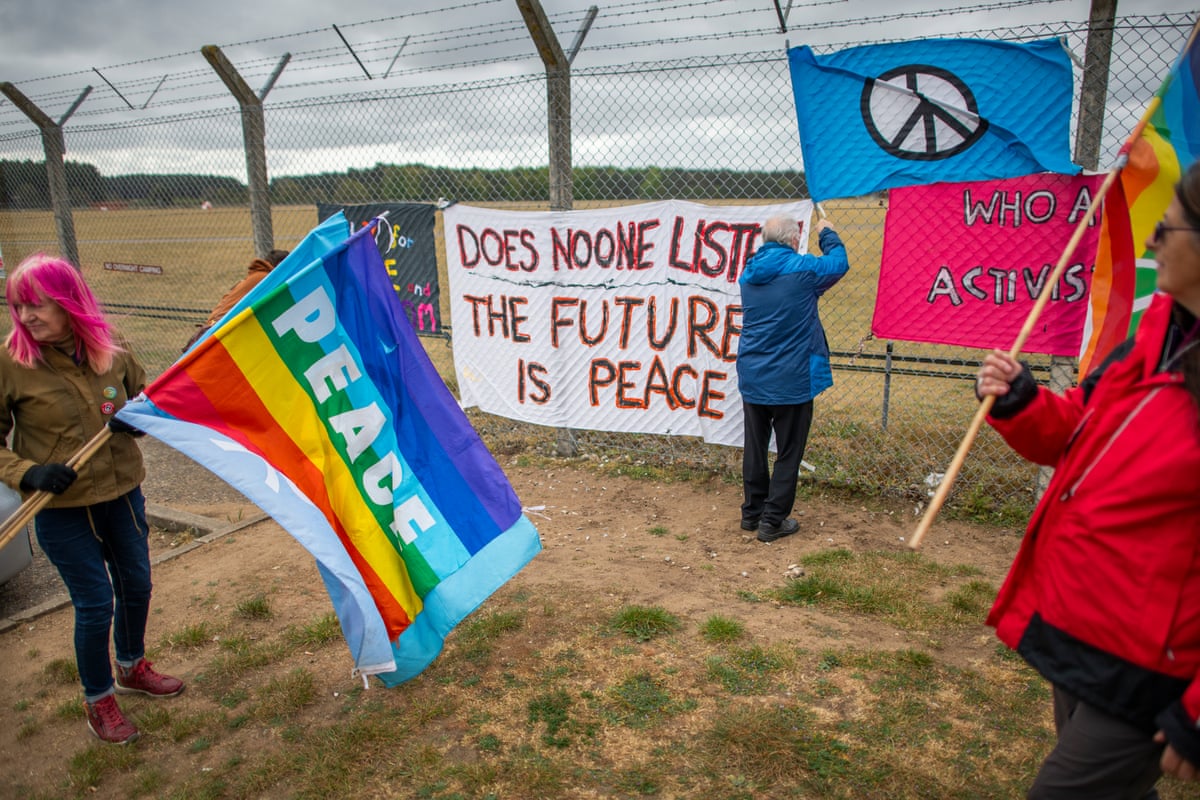 People with banners calling for peace outside fence