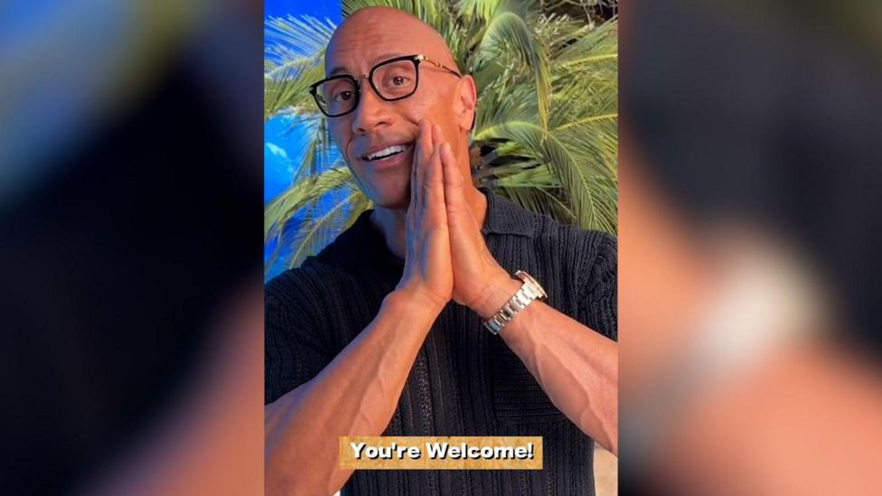 A screenshot of Dwayne Johnson's video to the students. The background is a tropical beach and the caption reads 