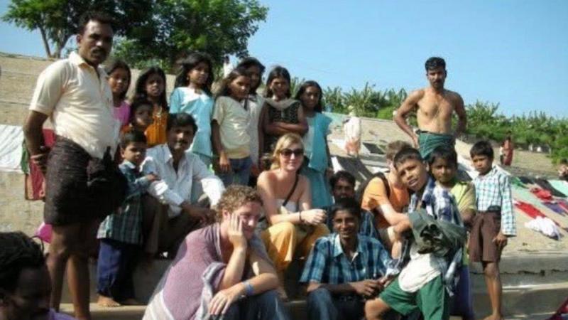 Lowri sitting on steps with a large group of locals in India