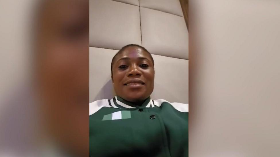 Portrait image of Goodness Chiemerie Nwachukwu (taken on a phone). She is black and has dark hair tied back. She's wearing a green and white sports jacket and looking straight at the camera