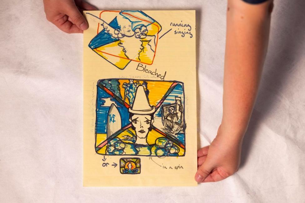 A piece of paper with illustrations including a man with clown make-up and a hat, and the words 'running singing' 'bleached' and 'in a spin'