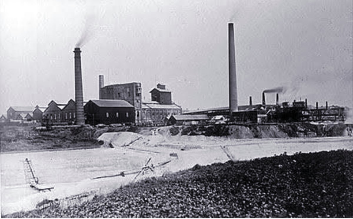 A black and white image of buildings and towers emitting smoke