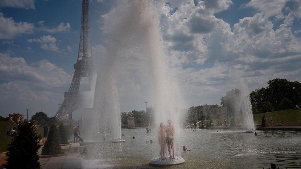 A photo of people cooling off in a fountain in Paris near the iconic Eiffel Tower 