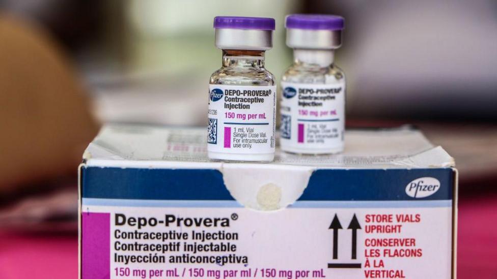Two small bottles Depo Provera sitting on top of a Pfizer box