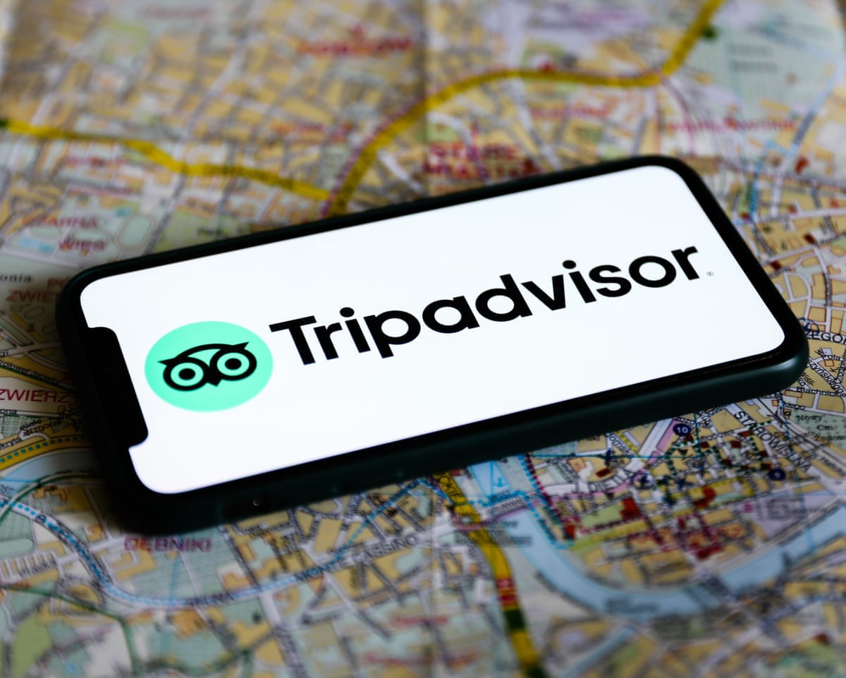 Tripadvisor logo on a phone which is placed on a paper map