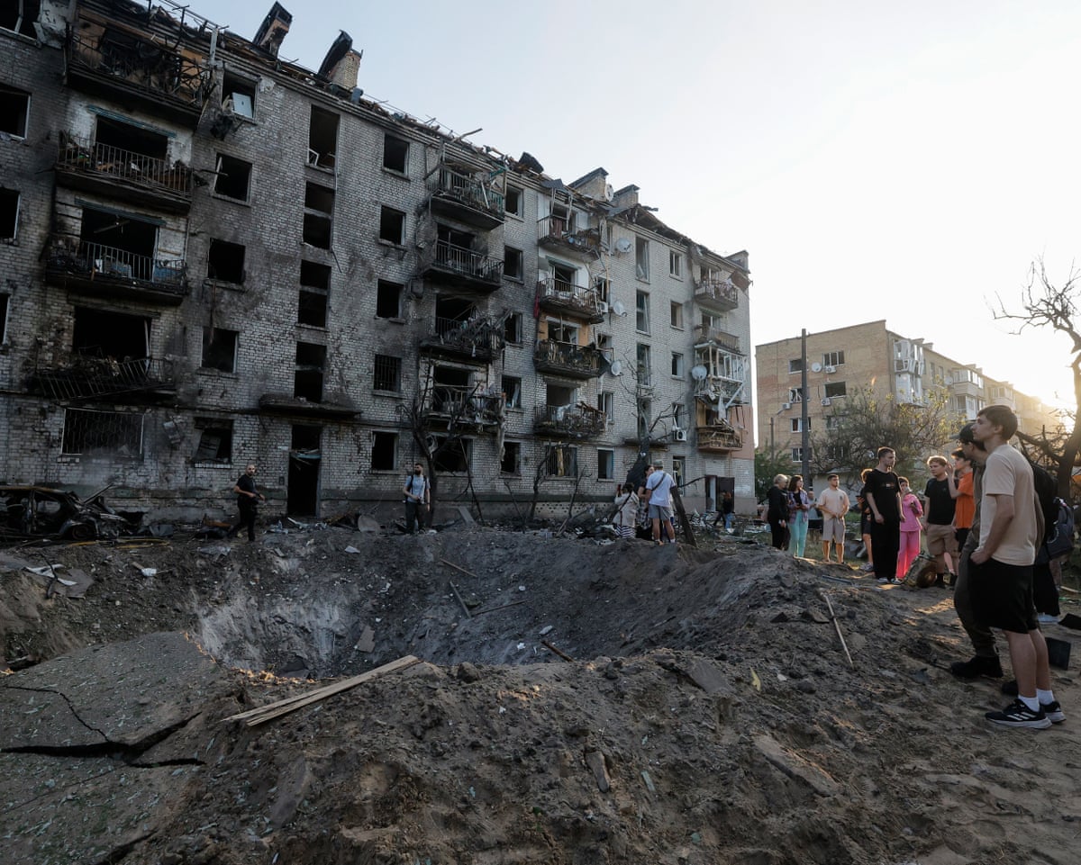 Local people look at a crater at the site of a Russian missile strike on a residential area in Kyiv, Ukraine.