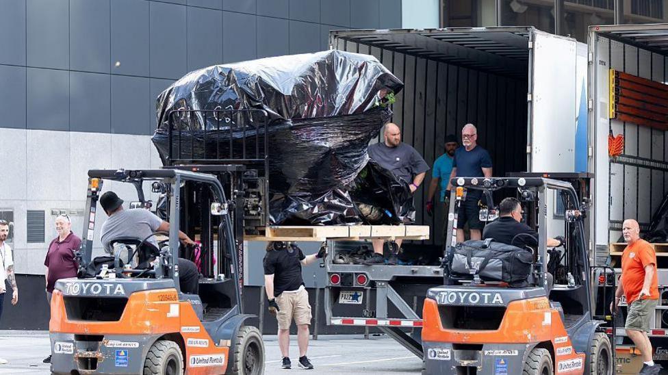 Crew members are seen unloading trucks and transporting large boxes and items under tarpaulin into Madison Square Garden in preparation for the rumored wedding of Taylor Swift and Travis Kelce