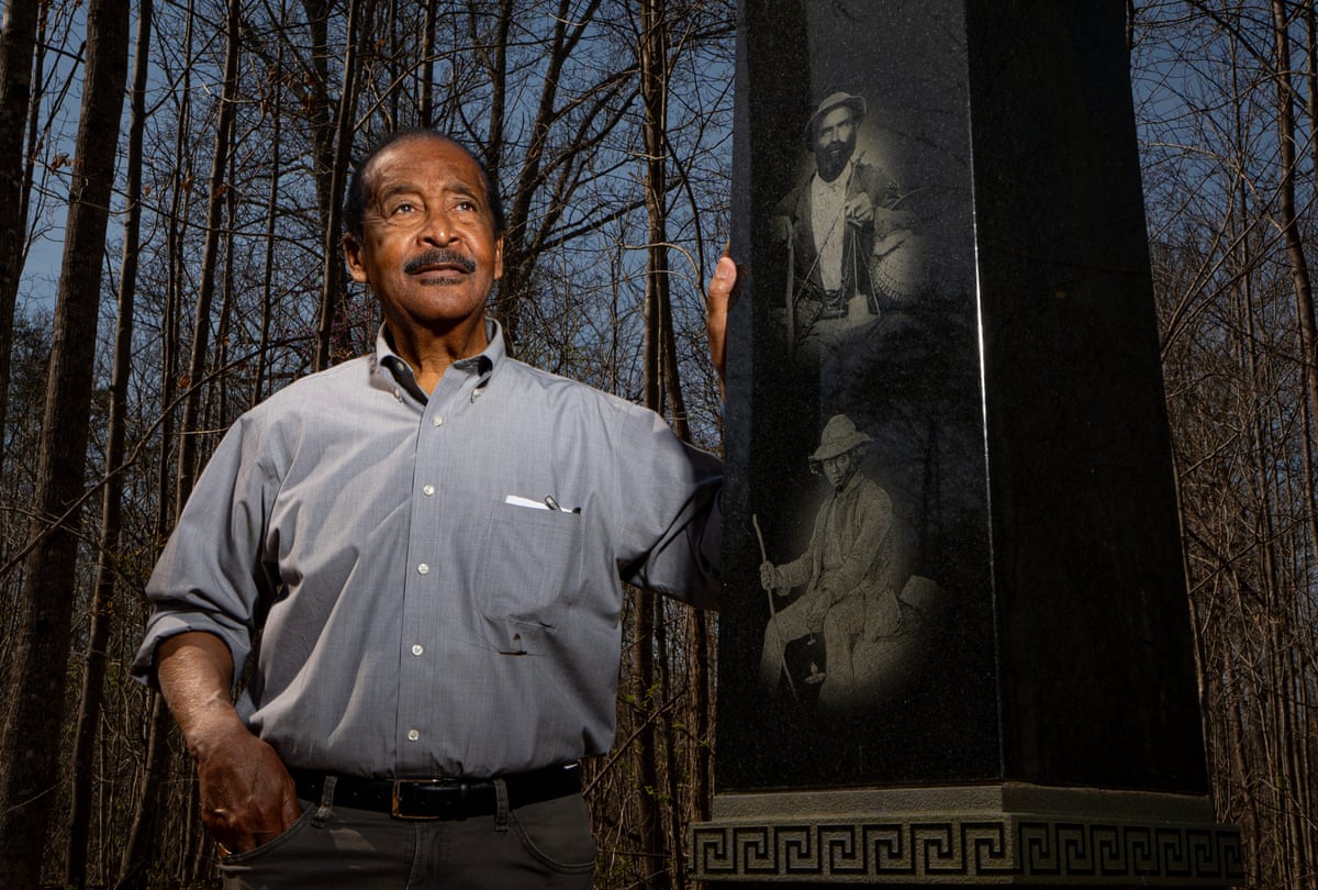 a man standing next to an outdoor monument surrounded by trees