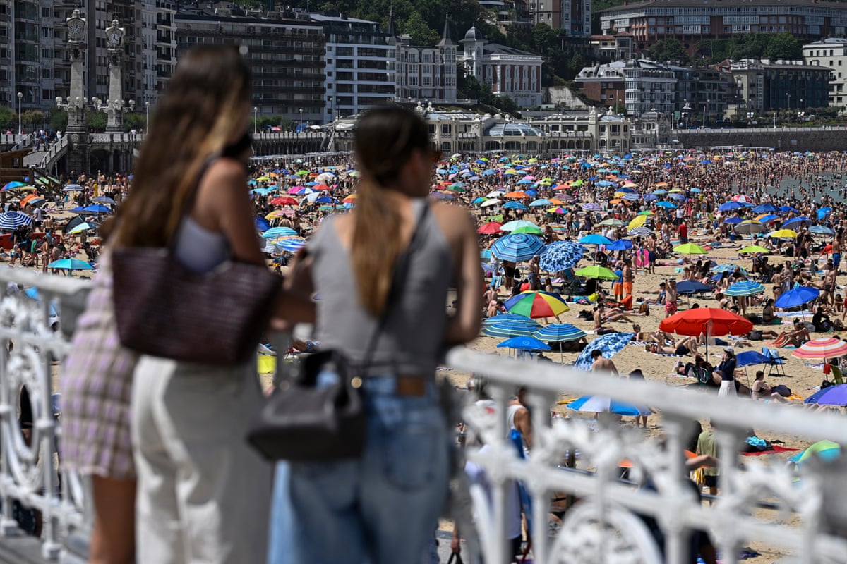 Three woman look at a packed beach.