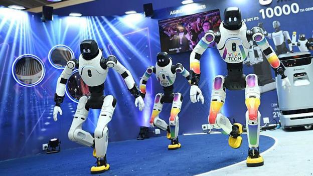 Three humanoid robots perform a dance routine.