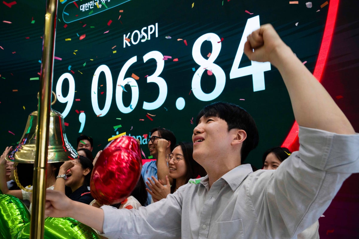Workers celebrate as a display shows South Korea’s KOSPI index at an all-time high closing price of 9,063.84.