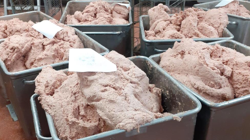 Six large grey metal containers of pink soft-looking paste which will be made into kebabs