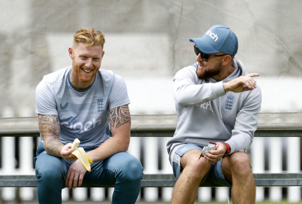 Ben Stokes on a bench eating a banana and laughing as Brendon McCullum talks in May 2022