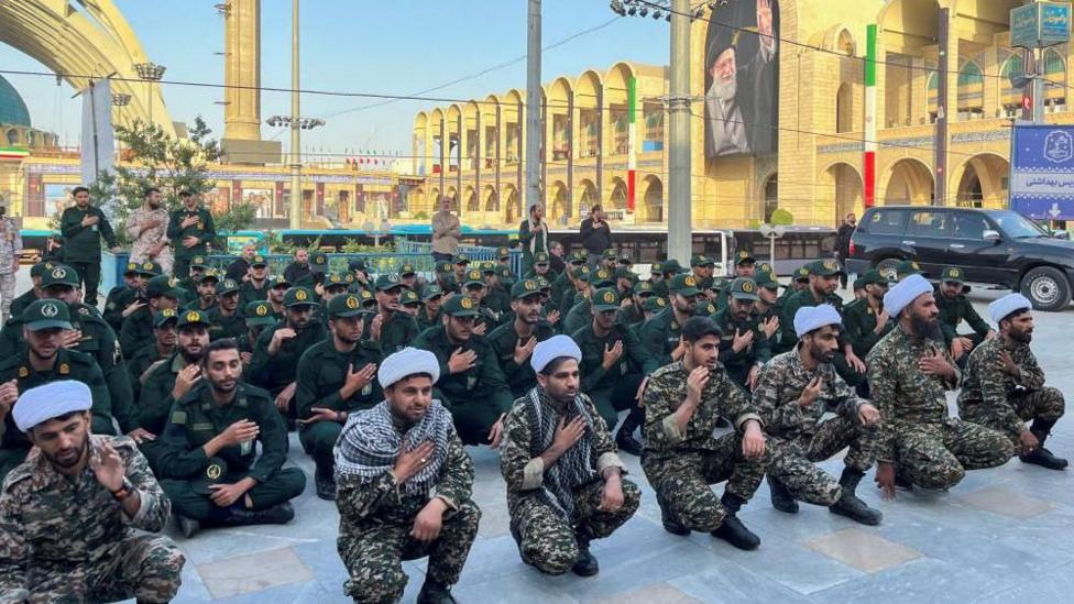 About 50 members of the Basij paramilitary on their knees with their hands on their chests in respect of the late Ayatollah Ali Khamenei