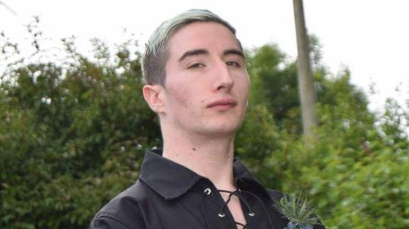 Thomas Fraser has blonde dyed hair swept to one side. He is wearing black dress shirt usually worn with a kilt.
