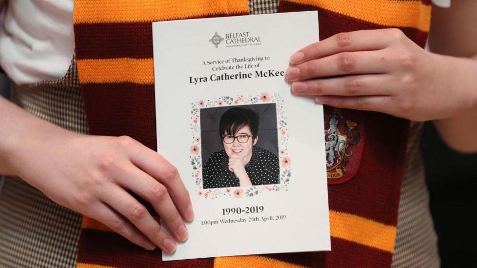 A mourner wearing a Gryffindor scarf from the Harry Potter series holds an order of service as they arrive to attend the funeral service of journalist Lyra McKee