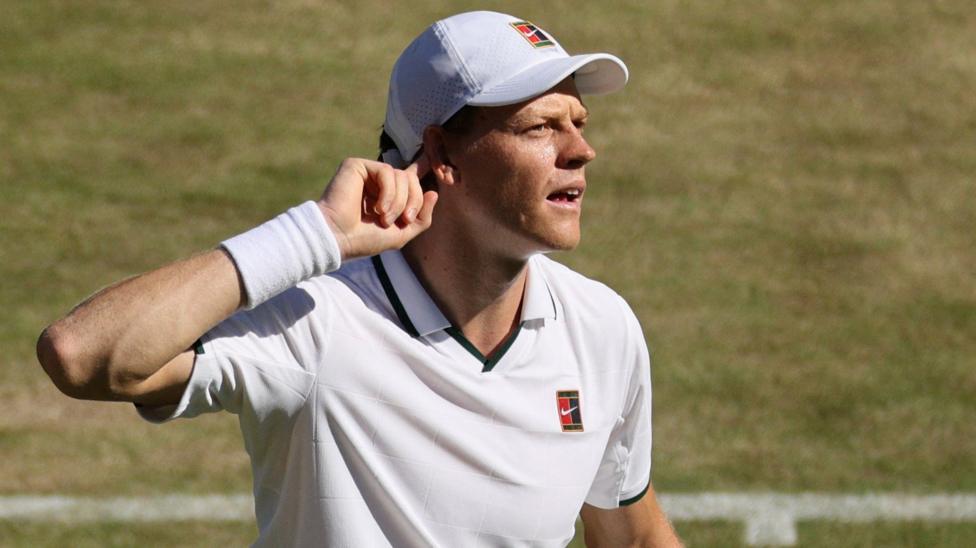Jannik Sinner points his finger to his ear