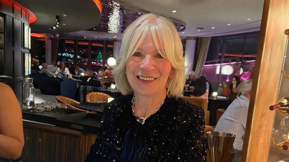 Violet Black sitting in a restaurant in a sparkly top