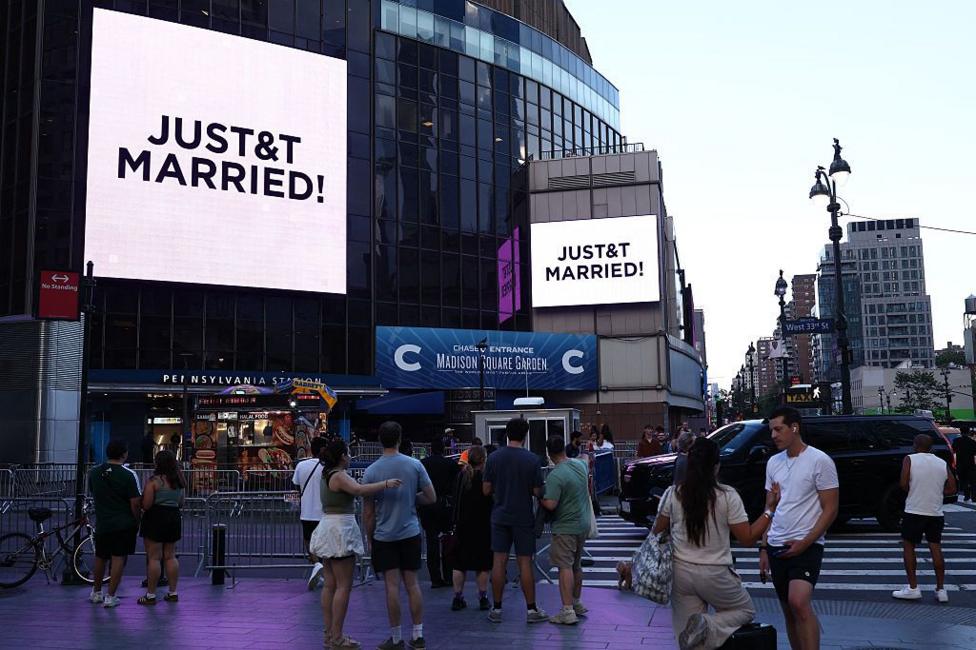 People watch giant screens showing the message 