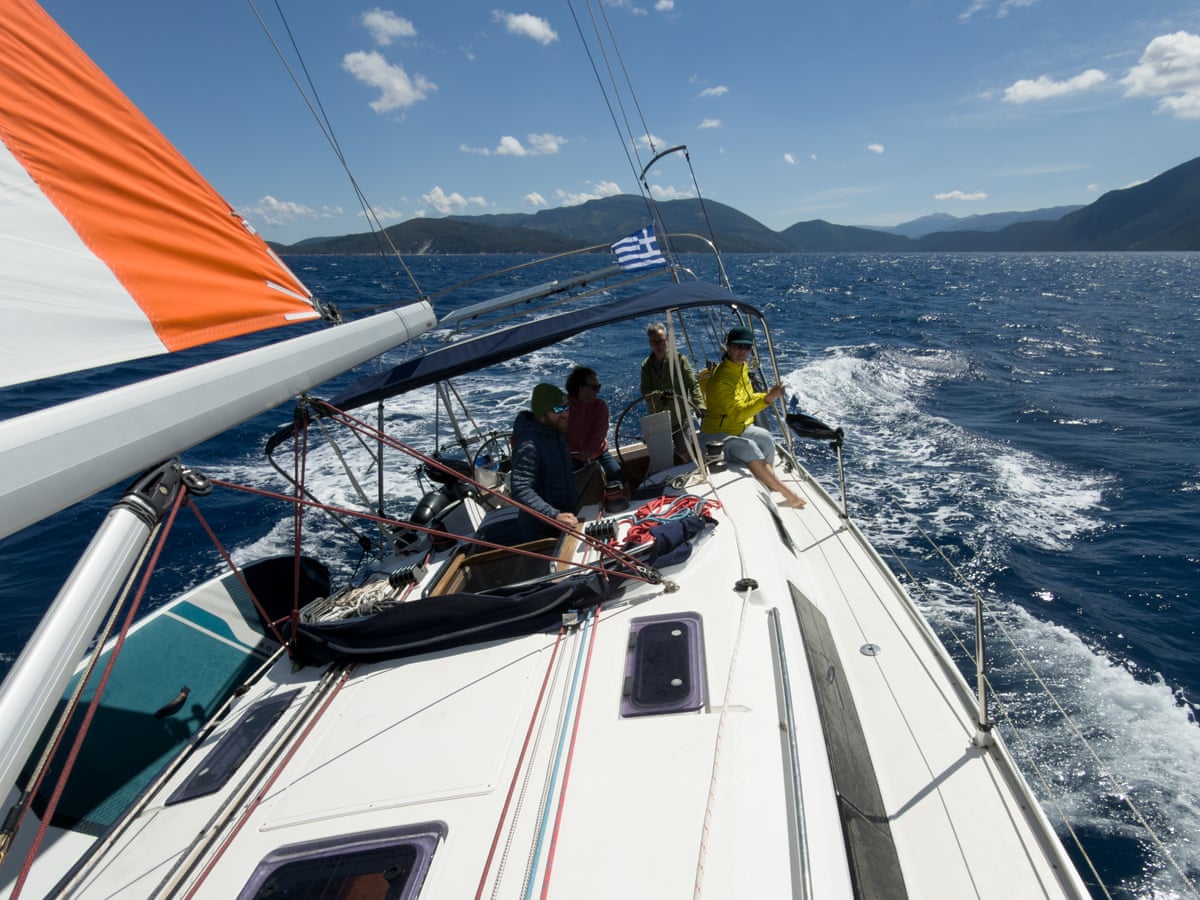 People sitting on the bow of a sailing boat with an island ahead