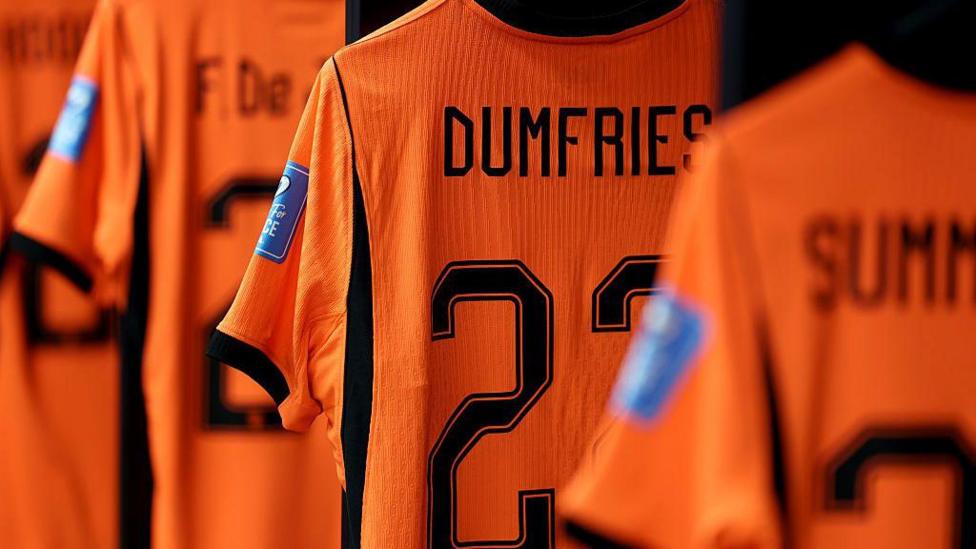 A set of Dutch bright orange football strips one with the name Dumfries clearly visible on its back