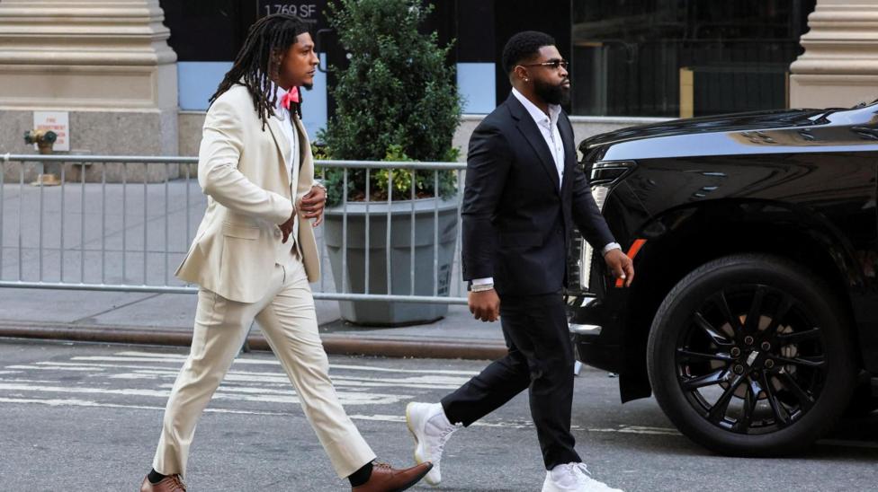 NFL athlete Isiah Pacheco arrives at Madison Square Garden wearing a cream suit and tan shoes.