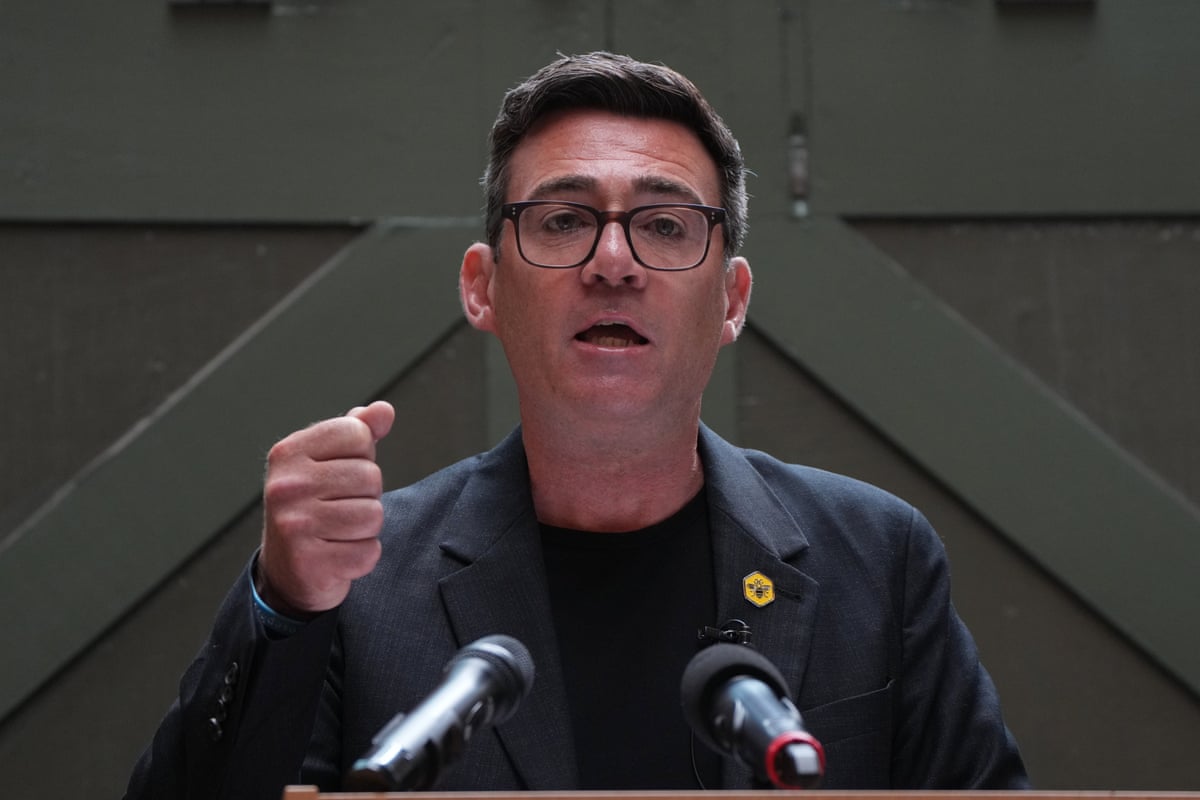 Andy Burnham makes a speech in a black jacket against a green wooden door