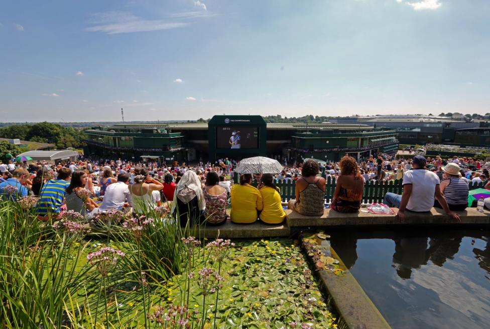 Taken at the top of Henman Hill thousands of fans are sitting in the sunshine watching tennis on the big screen outside Centre Court
