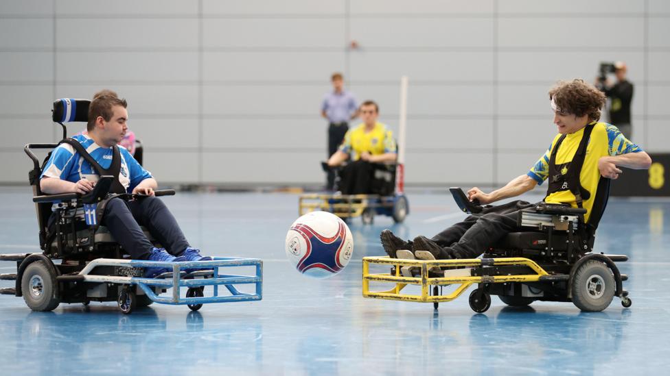 Two players contest the ball during the game. The player on the right, is from Leeds PFC and wears a yellow shirt - the opponent in blue.