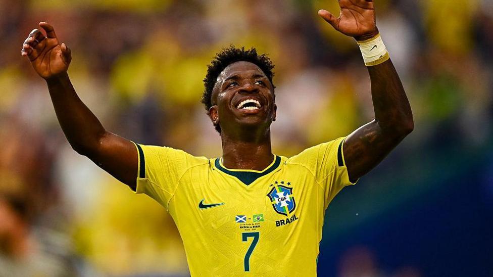 Vinicius Jr celebrates with arms raised and a broad smile after scoring for Brazil against Scotland at the World Cup