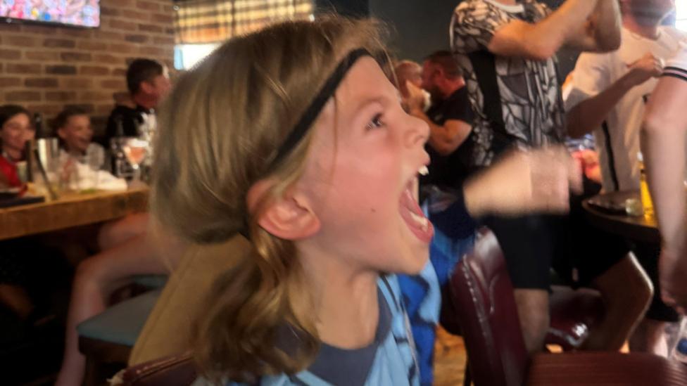 A young child is cheering on England