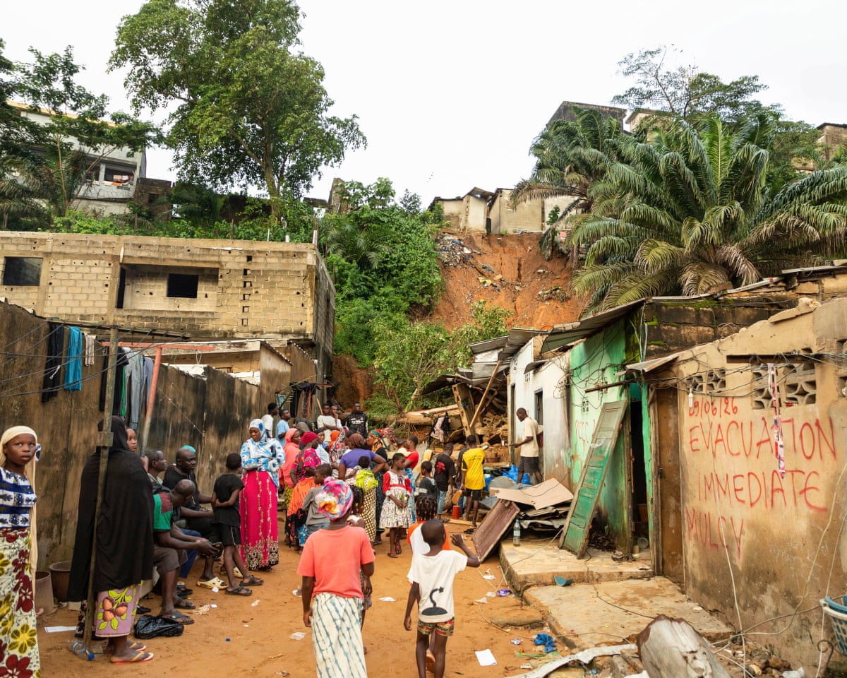 Residents gather among houses damaged by landslides and flooding in Attécoubé