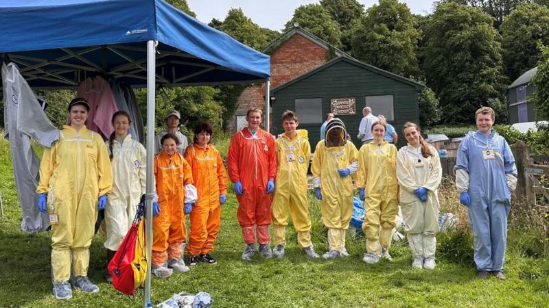 Beekeepers wearing a range of different suits such as yellow, white, orange and blue.