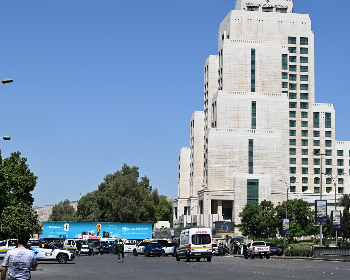 Syrian police officers and emergency personnel gather near the Four Seasons Hotel following two explosions nearby in Damascus.