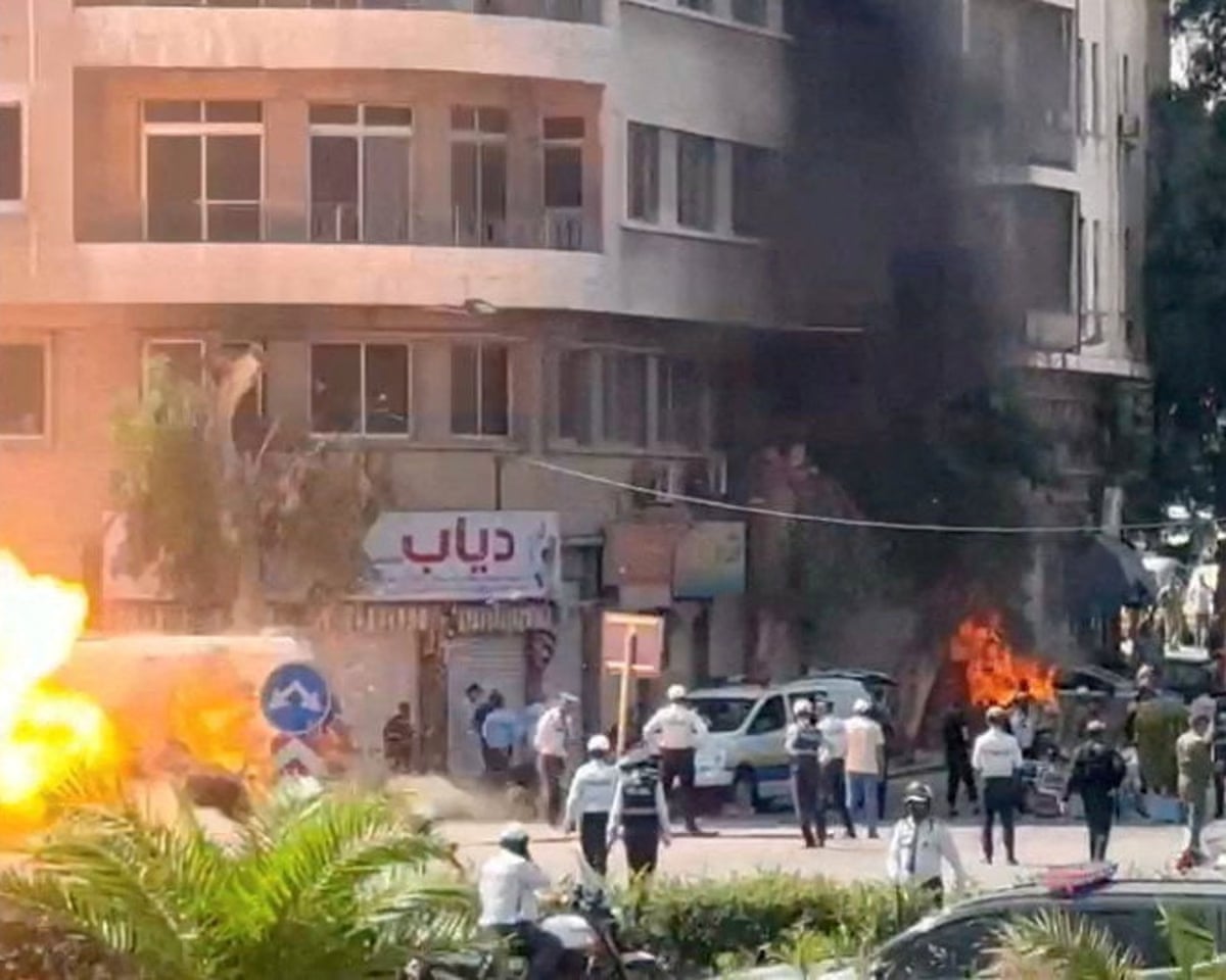 Emergency personnel work as smoke and fire rise at the site where explosive devices blew up near a hotel where French president Emmanuel Macron was meant to be staying, in Damascus, Syria.