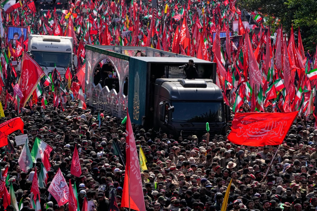 A sea of mourners carrying flags surround the truck carrying the body Khamenei and members of his family.