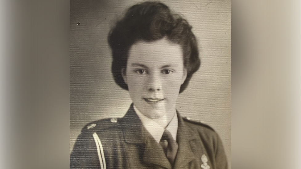 An old black and white picture of a woman with thick dark hair and wearing a military uniform.